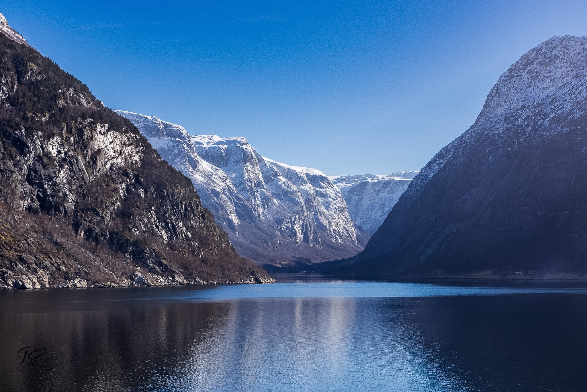 RIB boat speeding through the Eidfjord with mountain reflections in the water